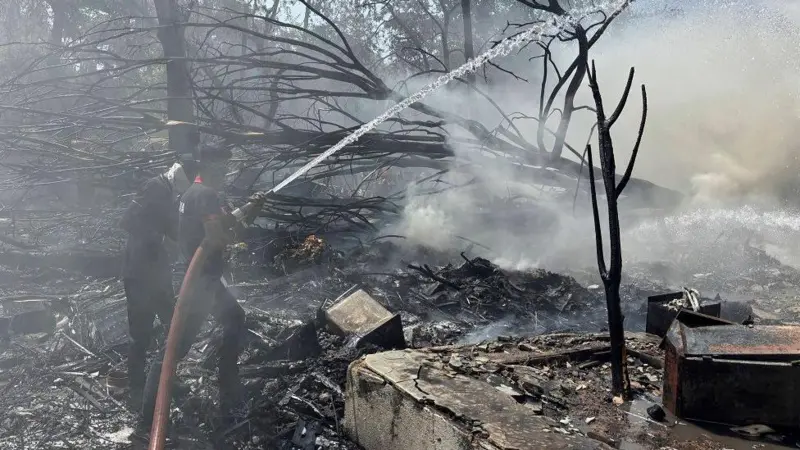 Rescatistas en el lugar del accidente. Uno de ellos rociando agua con una manguera
