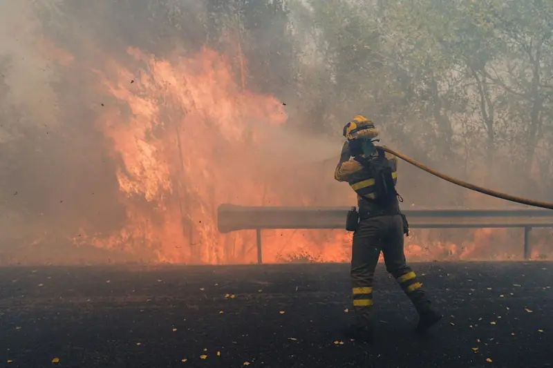 Bombero lanzando agua con una manguera para apagar un incendio