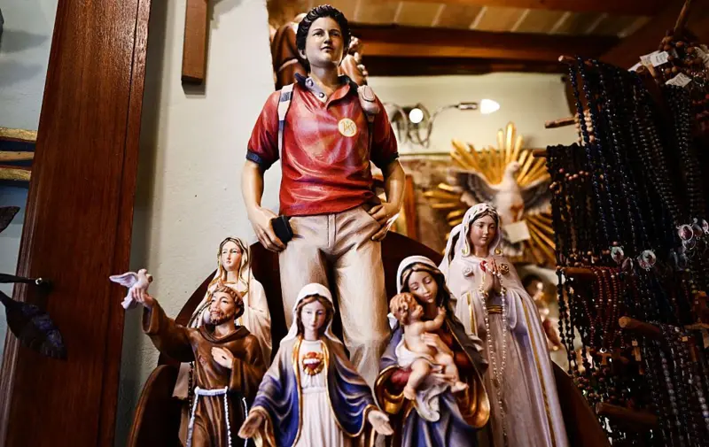 Una figura de Acutis junto a varias de la virgen María y una de San Francisco de Asís